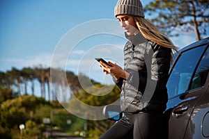 Young Woman Standing Next To Broken Down Car Trying To Get Signal On Mobile Phone