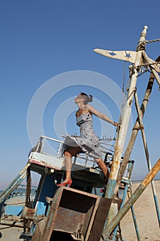 Young woman standing on an old boat looking at the sky