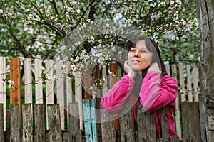 Young woman standing by old fence and dreamy looking