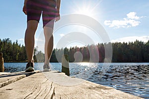 Young woman standing on an old wooden dock and pier at a lake.