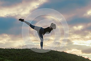 Young Woman Standing On One Leg And Exercising On the Grass Morning Workout, Beautiful Sunrise