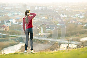 Young woman standing outdoors enjoying city view. Relaxing, freedom and wellness concept