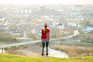 Young woman standing outdoors enjoying city view. Relaxing, freedom and wellness concept