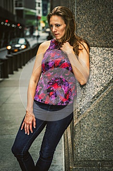 Young woman standing outdoors in New York City, looking down, thinking