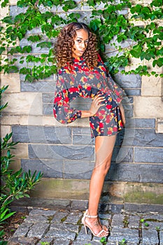 Young woman standing outdoors by wall in New York City, looking forward