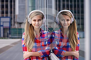 Young woman standing outside listening to music on headphones