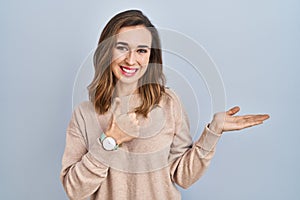 Young woman standing over isolated background showing palm hand and doing ok gesture with thumbs up, smiling happy and cheerful