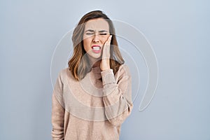 Young woman standing over isolated background touching mouth with hand with painful expression because of toothache or dental
