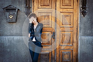 Young woman standing over old wooden door and holding head