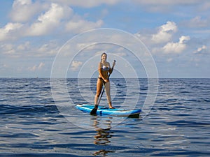 Young woman standing on paddleboard on sea surface. Sports activity paddleboarding. Stand up paddle. Girl enjoying sunny day at se