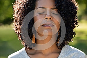 Young woman standing in a park with her eyes closed