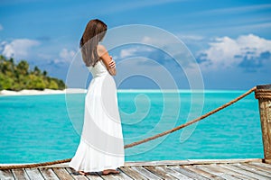 Young woman standing on a pier watching beautiful blue sea