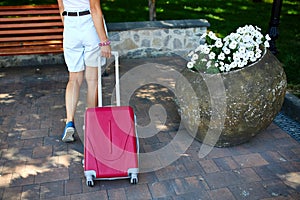 Young Woman Standing With Pink Suitcase by Park Bench on a Sunny Day