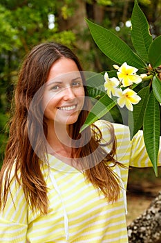 Young woman standing by plumeria tree photo