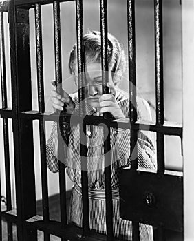 Young woman standing in a prison cell photo