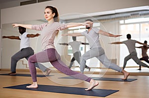 Young woman standing in Revolved High Lunge Pose during yoga class