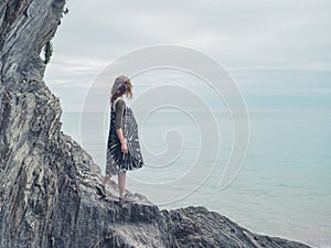 Young woman standing on rocks and looking at sea