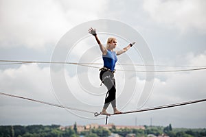 Young woman standing on the slackline rope and looking into the distance