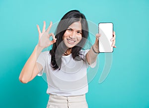 Young woman standing smile, holding mobile phone and showing ok gesture