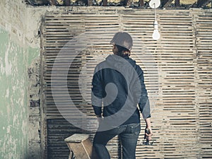 Woman standing on stepladder by wattle and daub wall