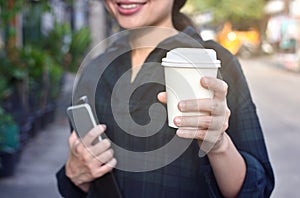 Young woman standing at the street drinking coffee to go