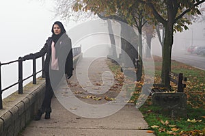Young woman standing on the street on foggy autumn day