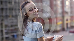 Young woman standing on sunset city street background and taking photo or video using smartphone