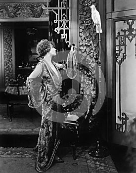 Young woman standing and talking to her parrot