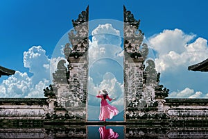 Young woman standing in temple gates at Lempuyang Luhur temple in Bali, Indonesia. Vintage tone.