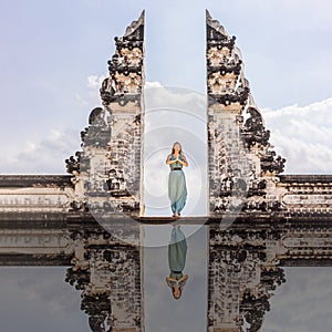 Young woman standing in temple gates at Lempuyang Luhur temple in Bali, Indonesia. Vintage tone. Bali, Indonesia