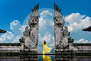 Young woman standing in temple gates at Lempuyang Luhur temple in Bali, Indonesia. Vintage tone photo