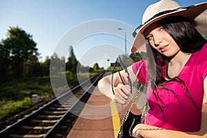 A young woman is standing on the train platform waiting for a late train to take her on the holiday journey of a