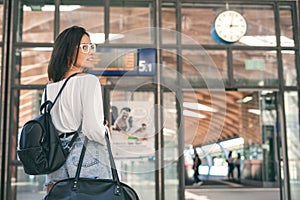 Young woman standing in the trainstation in front of timetables