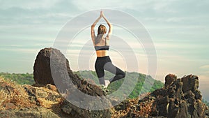 young woman is standing in the Tree Pose Vrikshasana in the park