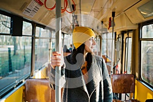 Young woman standing in a wagon of a driving tramway. Transportation, travel and lifestyle concept