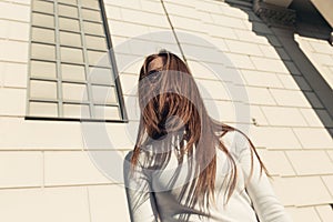 Young woman standing on the wall of the bilding backgroundand looking at camera photo