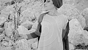 A young woman stands against a background of mountains and stones with magic grass. Enchantress. black and white image