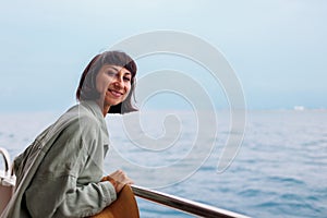 young woman stands on the deck of a cruise ship and enjoys the journey. woman on a yacht on vacation, vacation and travel. A young