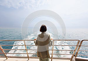 young woman stands on the deck of a cruise ship and looks at the water. woman on a yacht on vacation, vacation and travel. A young