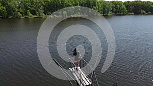 A young woman stands on the dock and looks at the water.