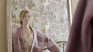 A young woman stands in front of a mirror and gets dressed before going out on a date. Lifestyle and beauty concept