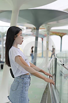 Young woman stands hands on handrail
