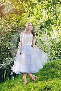 Young woman stands on a hill against the background of flowering trees