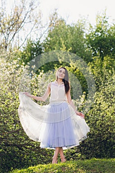 Young woman stands on a hill against the background of flowering trees