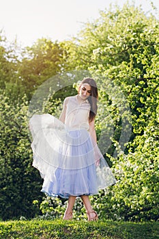 Young woman stands on a hill against the background of flowering trees