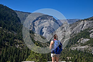 Young woman stands looking at the view in Yosemite National park.