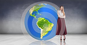 Young woman stands near big earth ball