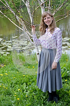 The young woman stands near the blossoming birch of useful Himalaya Betula utilis D. Don