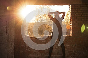 Young woman stands near the broken window in sunshine light