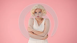 A young woman stands offended. Portrait of a woman in the image of Marilyn Monroe, wearing a white dress and white wig